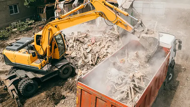 Excavator Loading Debris Into Truck at Demolition Site
